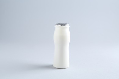 Tasty yogurt in bottle on light grey background