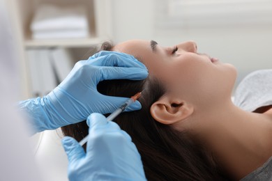 Trichologist giving injection to patient in clinic, closeup