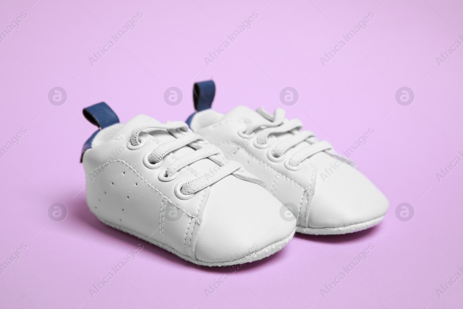 Photo of Pair of cute baby shoes on violet background