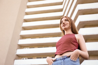 Photo of Beautiful young woman at modern building, low angle view
