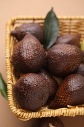 Photo of Delicious salak fruits in basket on pale brown background, above view
