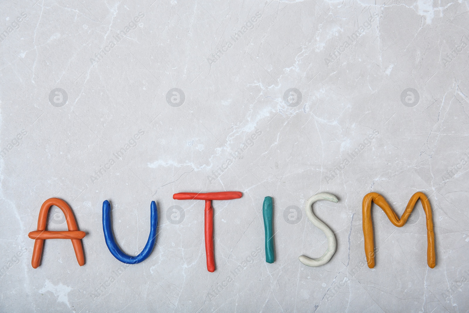 Photo of Word AUTISM made of plasticine on light background, top view