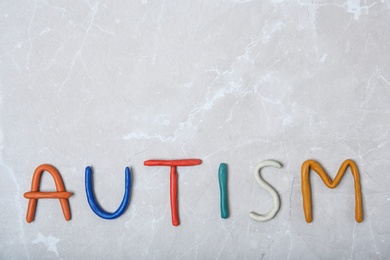 Photo of Word AUTISM made of plasticine on light background, top view