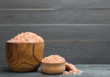 Photo of Pink himalayan salt on wooden table. Space for text