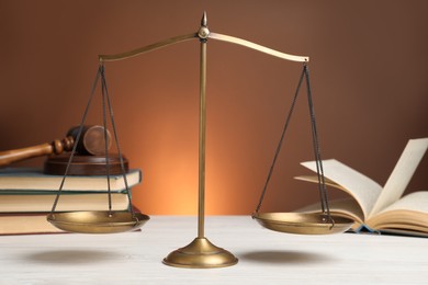 Photo of Scales of justice on white wooden table. Law concept
