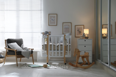 Photo of Baby room interior with crib, armchair and rocking horse. Idea for design