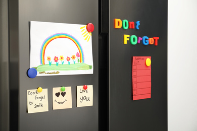 Photo of Modern refrigerator with child's drawing, notes and magnets