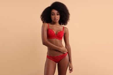 Photo of Beautiful woman in elegant red underwear on beige background