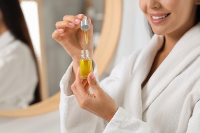 Young woman with serum in her hands in bathroom, closeup