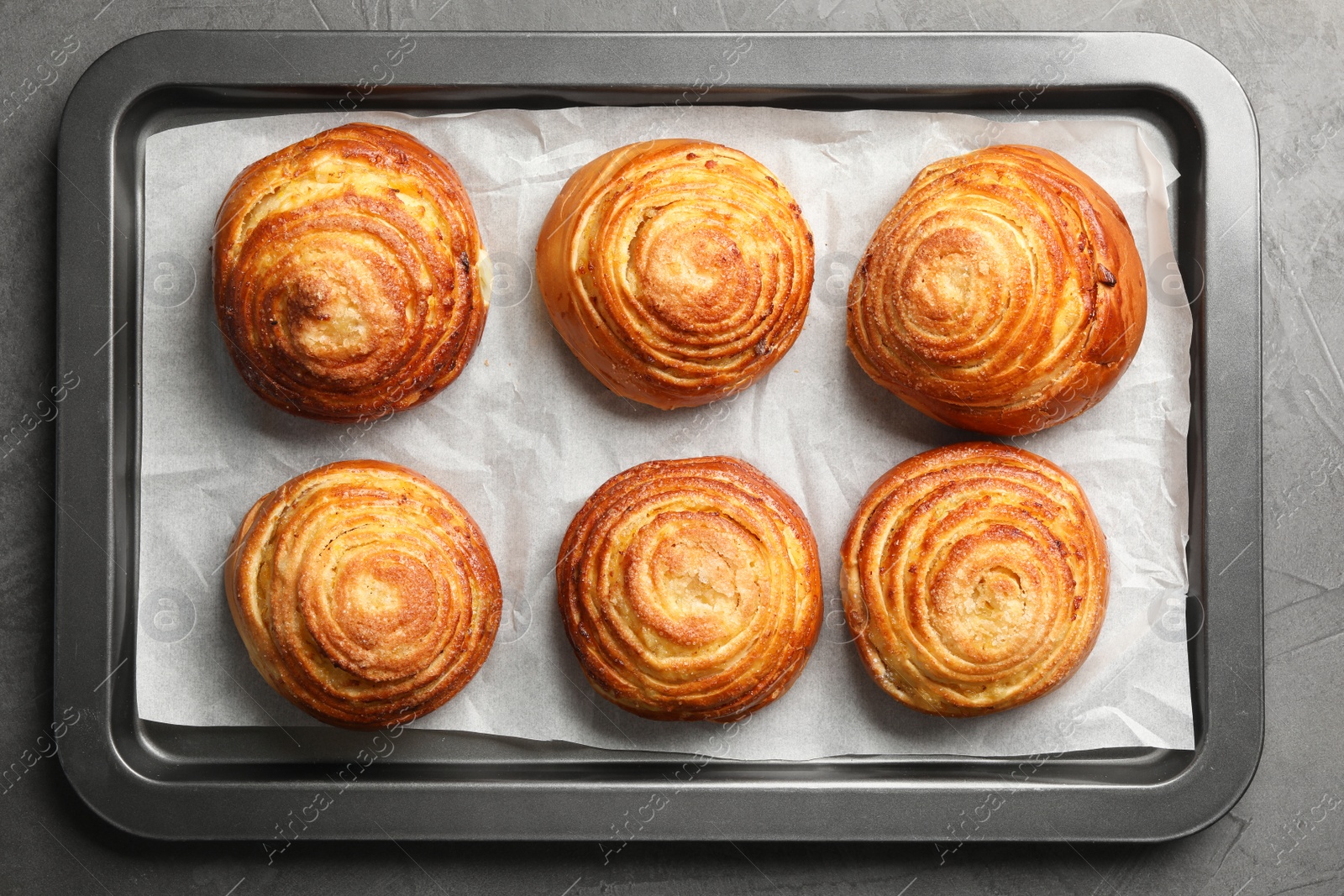 Photo of Baking sheet with buns on grey stone background, top view. Fresh from oven