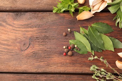 Aromatic bay leaves, different herbs and spices on wooden table, flat lay. Space for text
