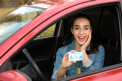 Photo of Happy woman showing driving license from new car