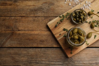 Photo of Tasty capers on wooden table, top view. Space for text