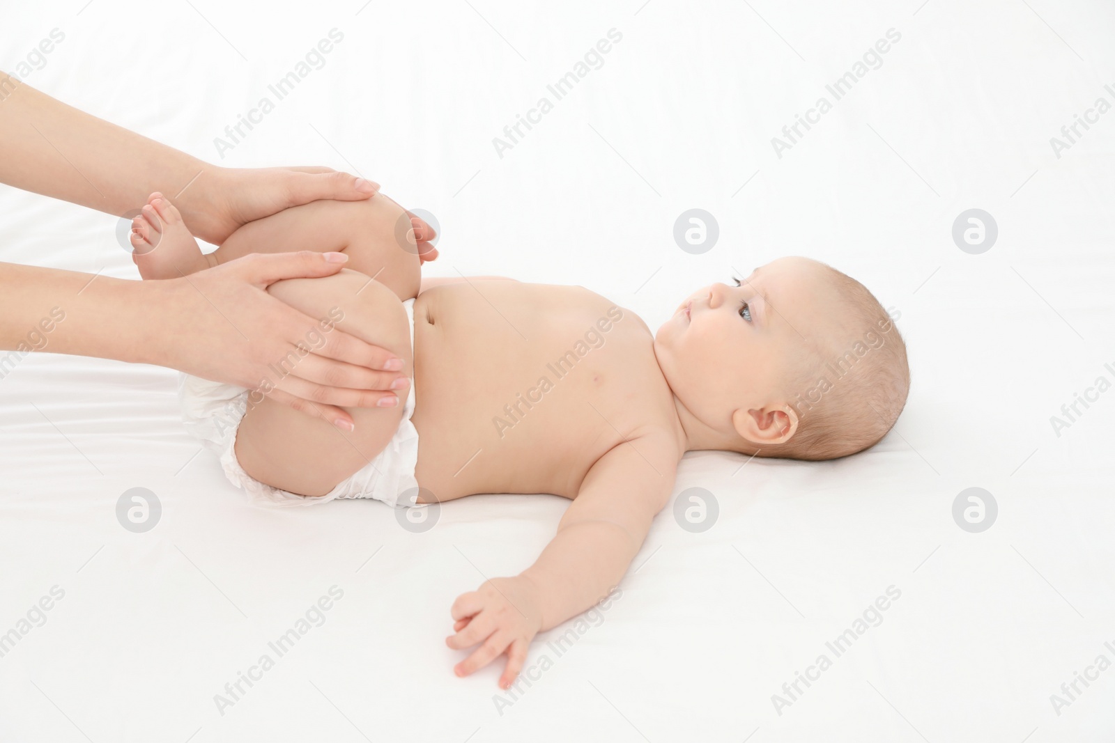 Photo of Mother and her cute child on white bed. Baby massage and exercises