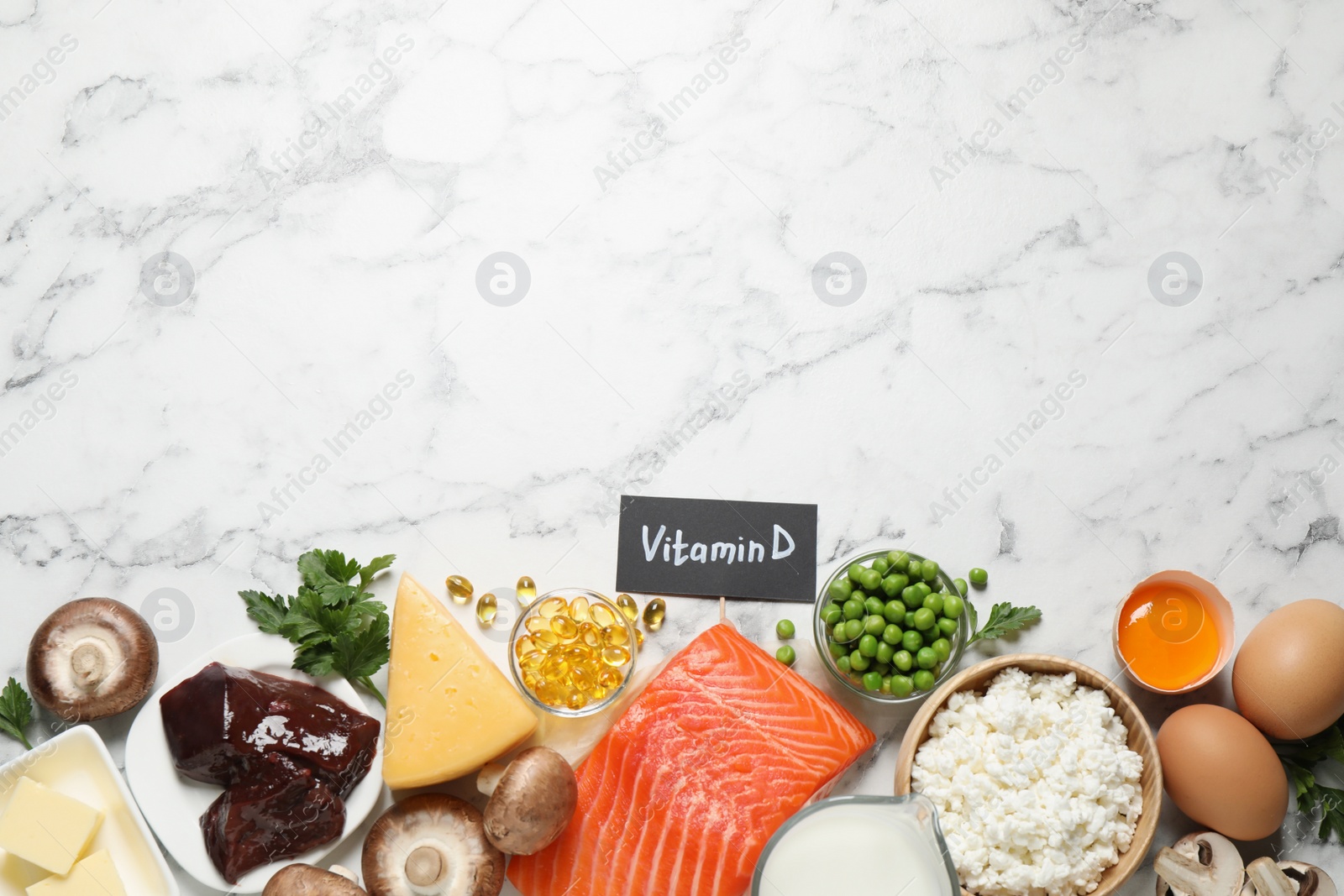 Photo of Flat lay composition with products rich in vitamin D on white marble table. Space for text