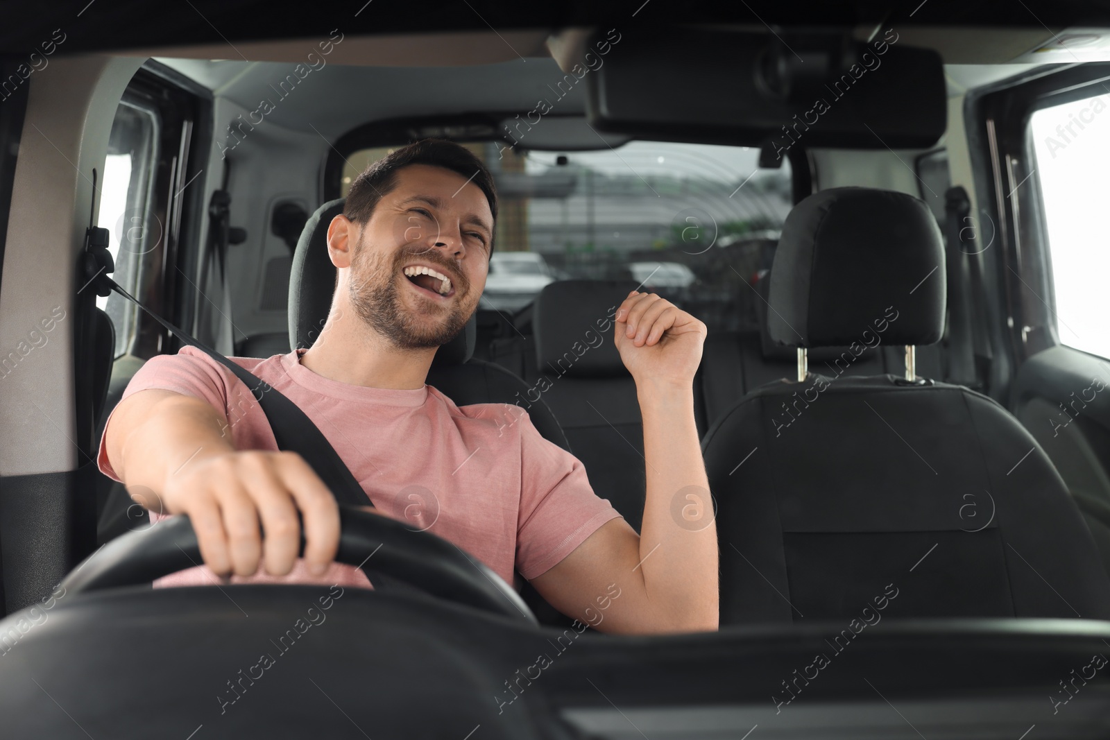 Photo of Listening to radio. Handsome man enjoying music in car, view through windshield