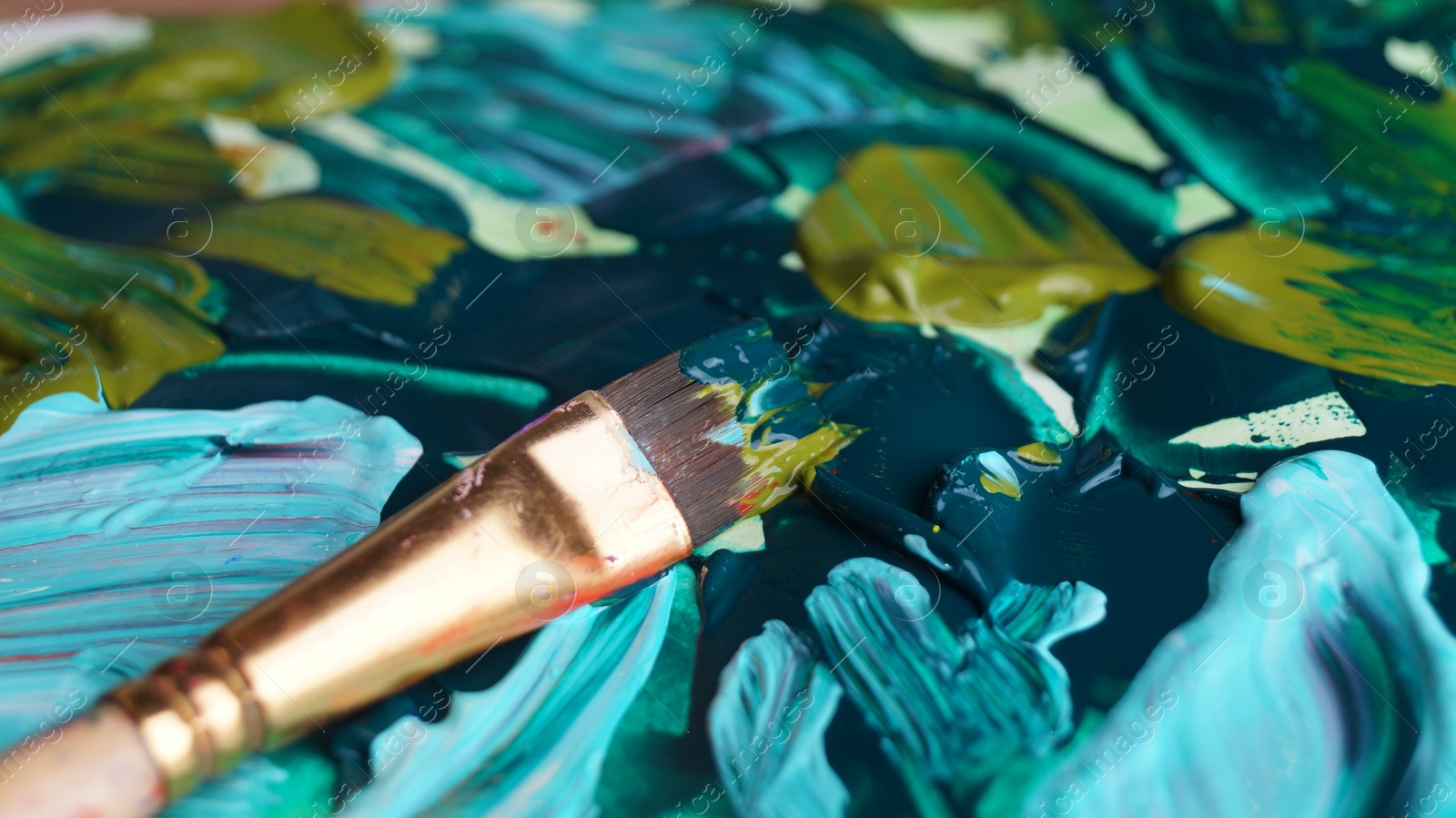 Photo of Brush on artist's palette with mixed paints, closeup