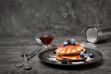 Tasty pancakes with syrup and berries on table