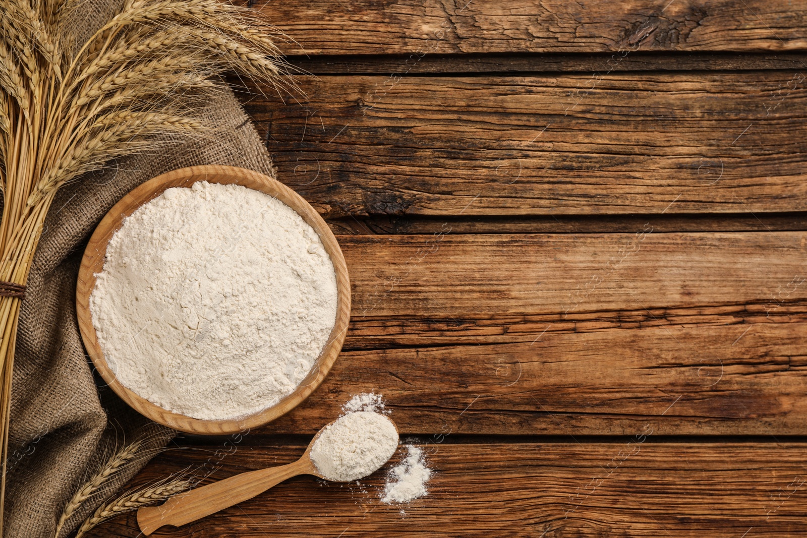 Photo of Flat lay composition with wheat flour on wooden table. Space for text