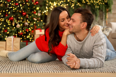Photo of Happy young couple lying on floor in living room decorated for Christmas