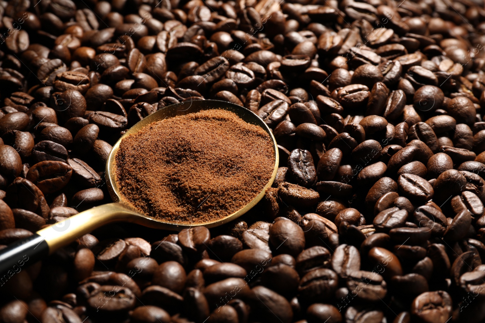 Photo of Spoon with ground coffee on roasted beans, closeup. Space for text