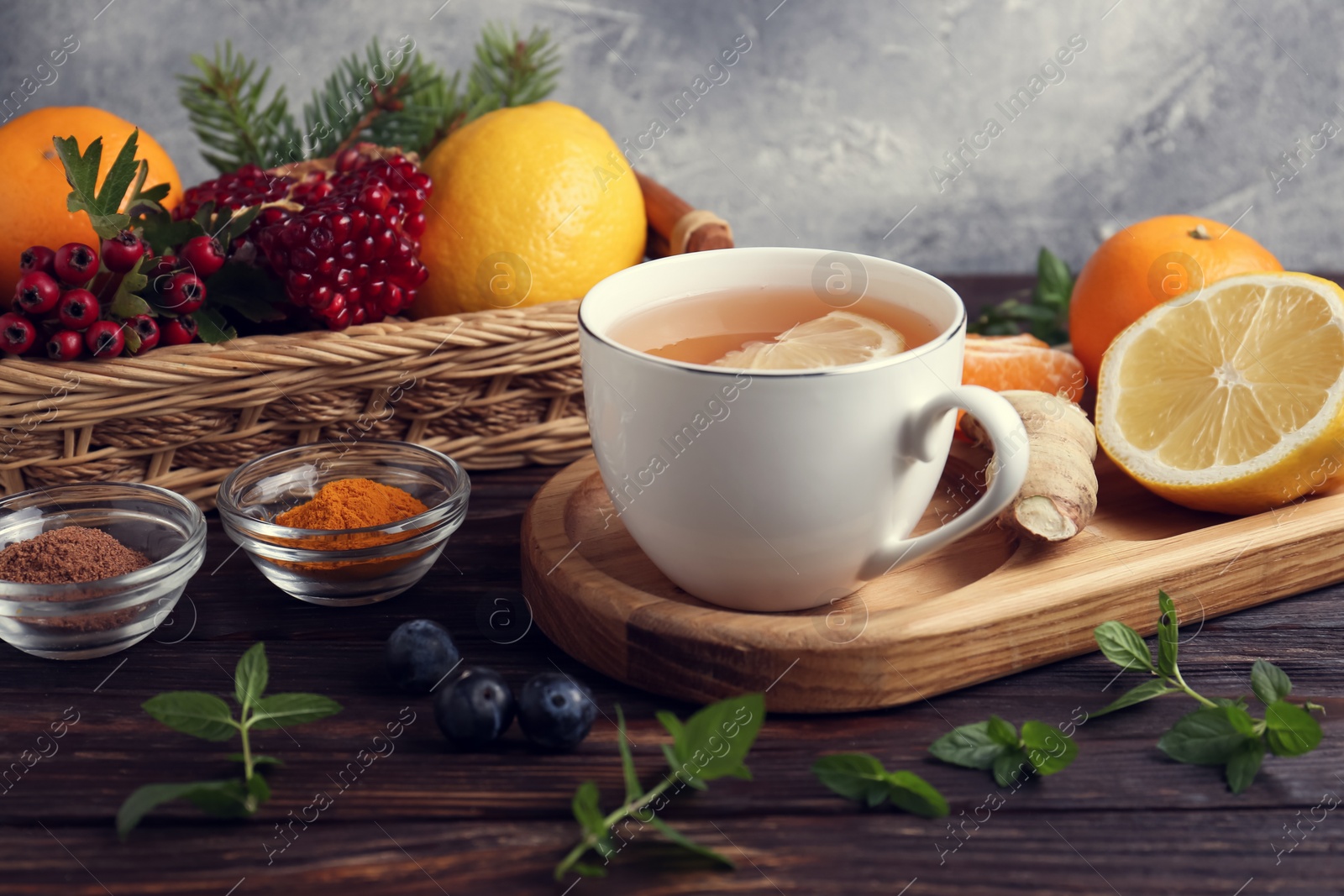 Photo of Cup of delicious immunity boosting tea and ingredients on wooden table