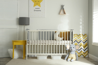 Photo of Cute baby room interior with crib and decor elements