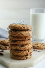 Photo of Tasty chocolate chip cookies and glass of milk on white wooden table, closeup