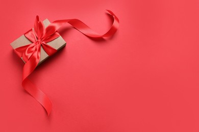 Beautiful gift box with bow on red background, top view. Space for text
