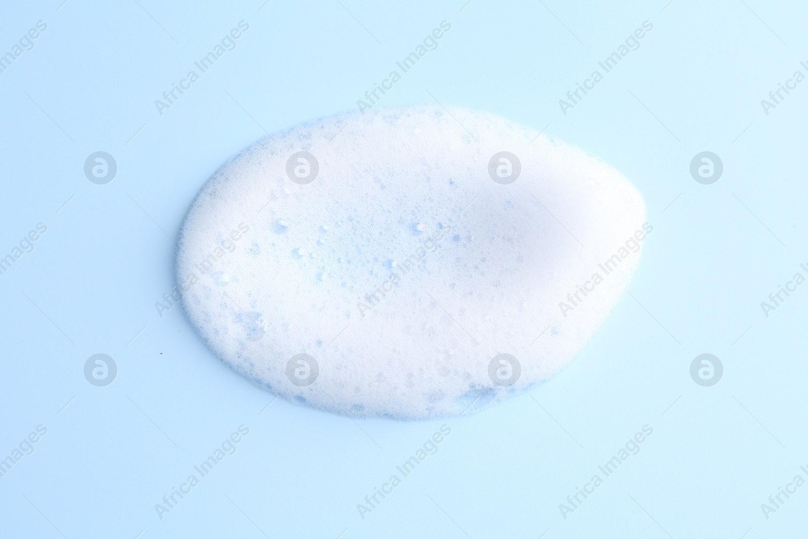 Photo of Sample of fluffy foam on light blue background, top view