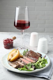 Photo of Delicious roasted beef meat, caramelized pear and greens served on light table