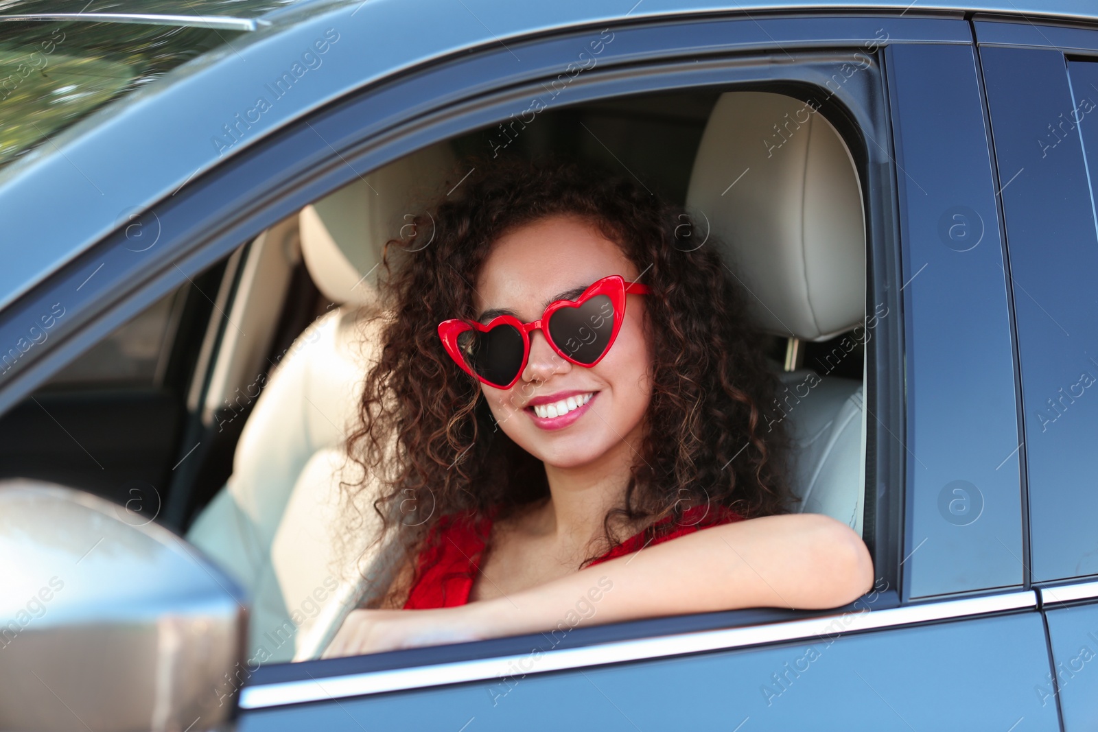 Photo of Young beautiful African-American woman wearing heart shaped glasses in car