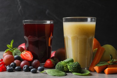 Photo of Delicious juices and fresh ingredients on grey table against black background