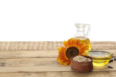 Photo of Sunflower, oil and seeds on wooden table against white background, space for text