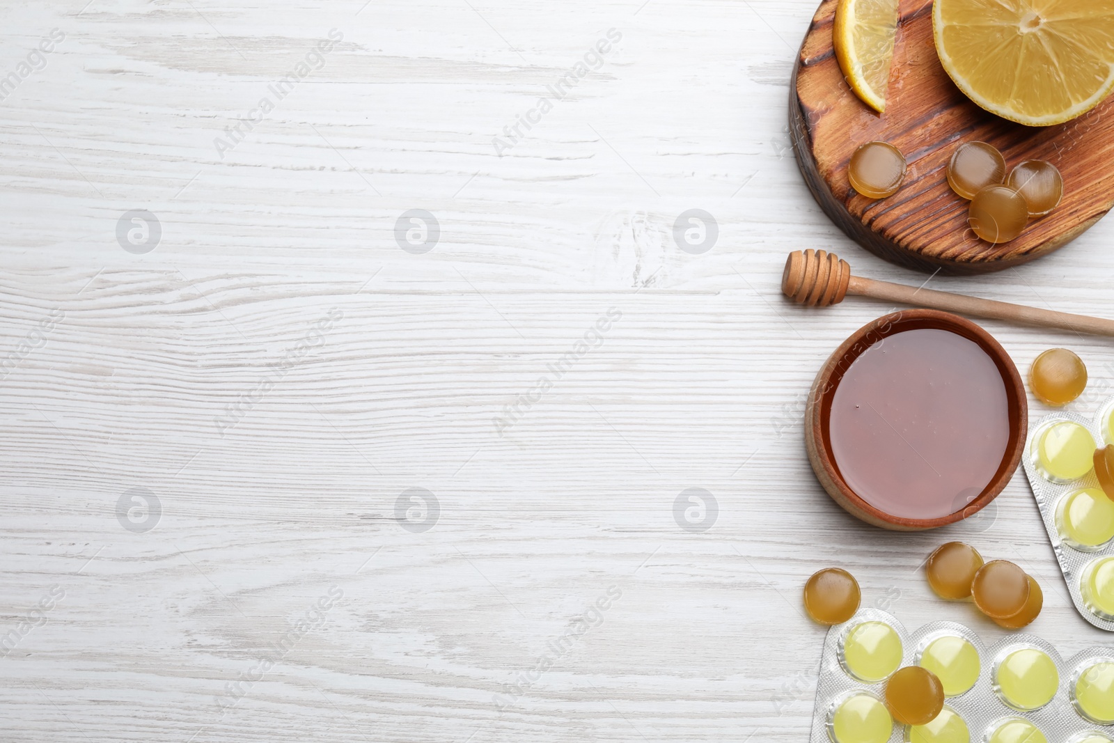 Photo of Cough drops, lemon and honey on white wooden table, flat lay. Space for text