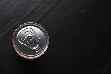 Photo of Energy drink in can on black textured background, top view. Space for text