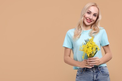 Photo of Happy young woman with beautiful bouquet on beige background. Space for text