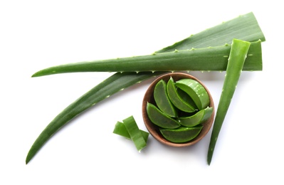 Bowl with pieces of aloe vera and green leaves on white background, top view