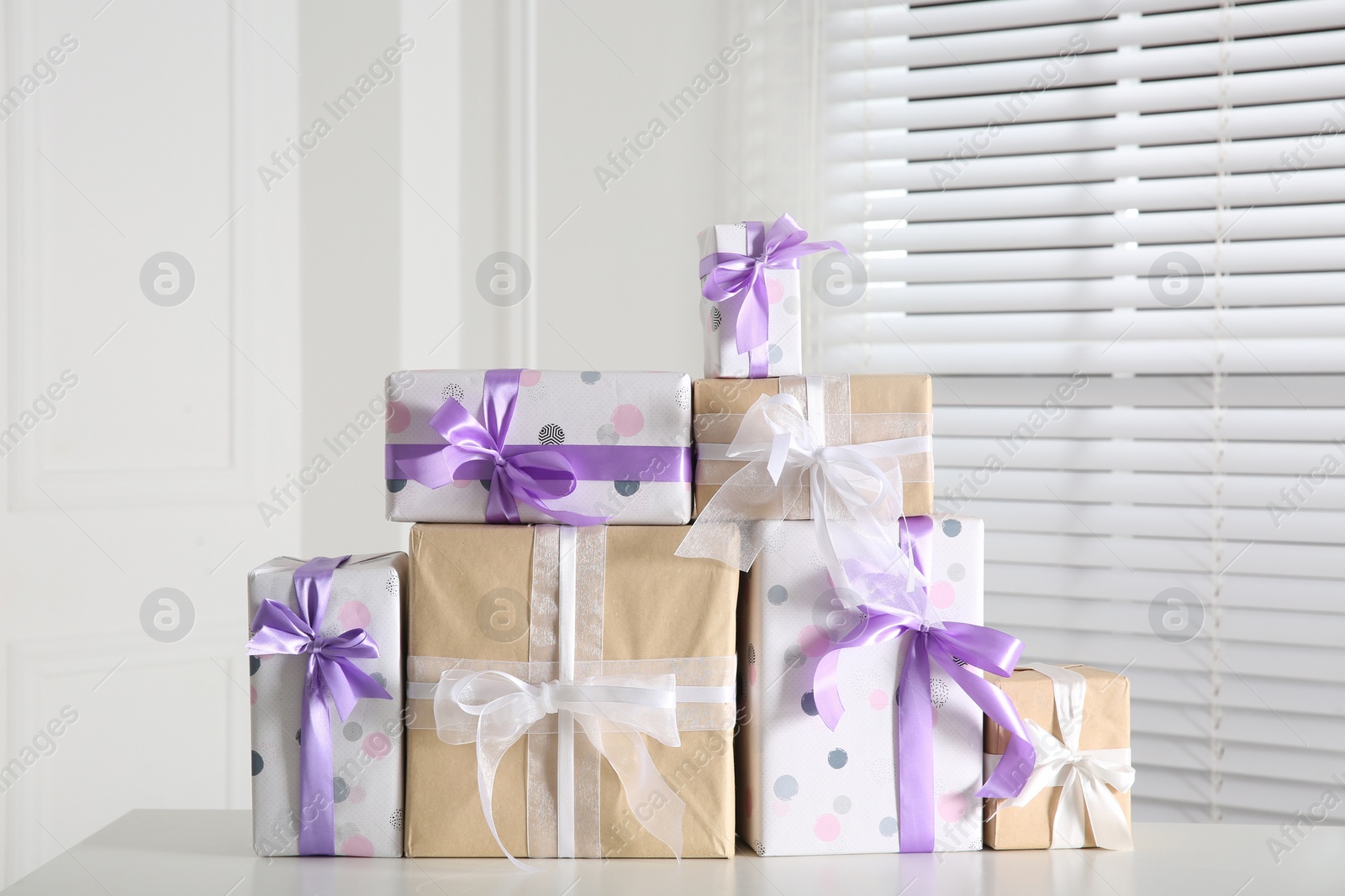 Photo of Heap of wrapped gift boxes on white table. Happy holiday