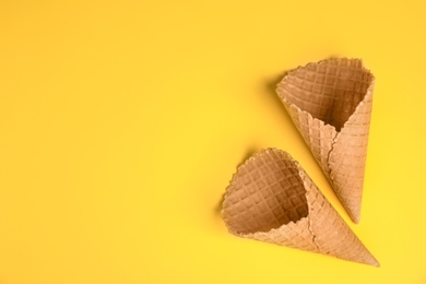 Photo of Waffle empty ice cream cones on color background, flat lay. Space for text