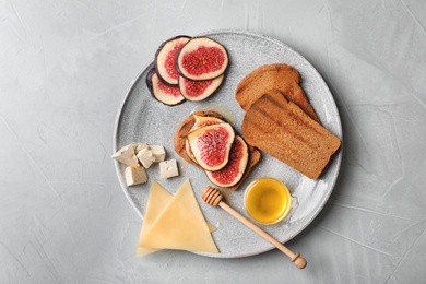 Photo of Plate with ripe figs and delicious products on grey background, top view