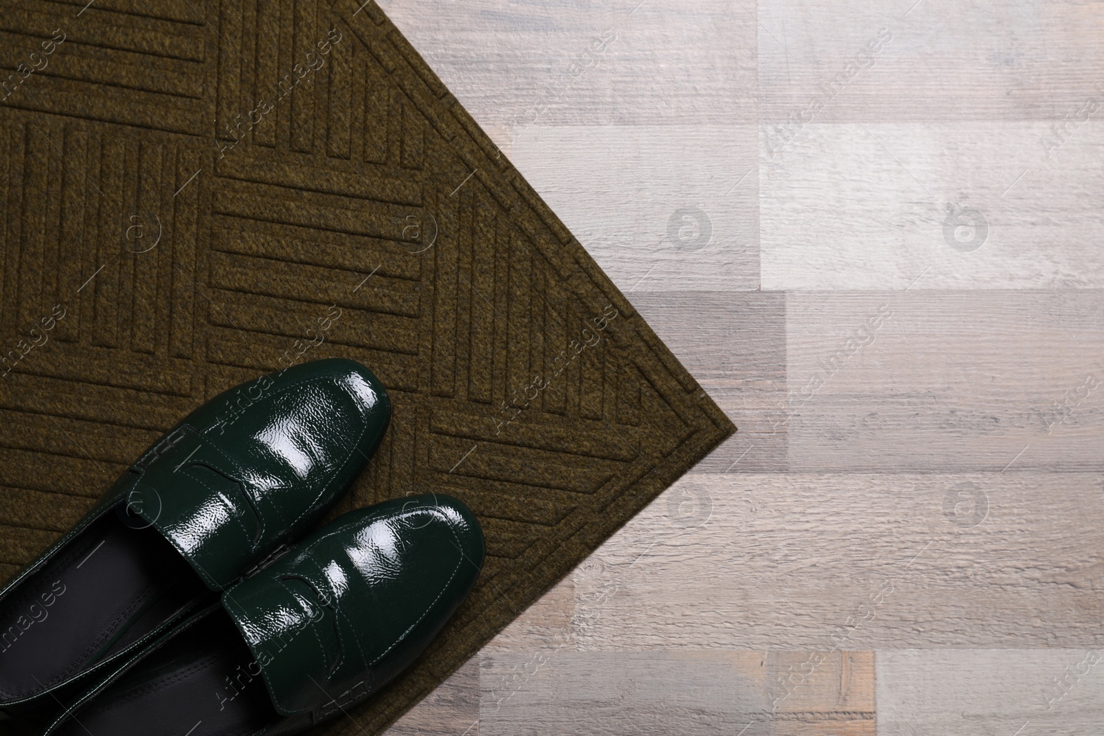 Photo of New clean door mat with shoes on floor, top view. Space for text