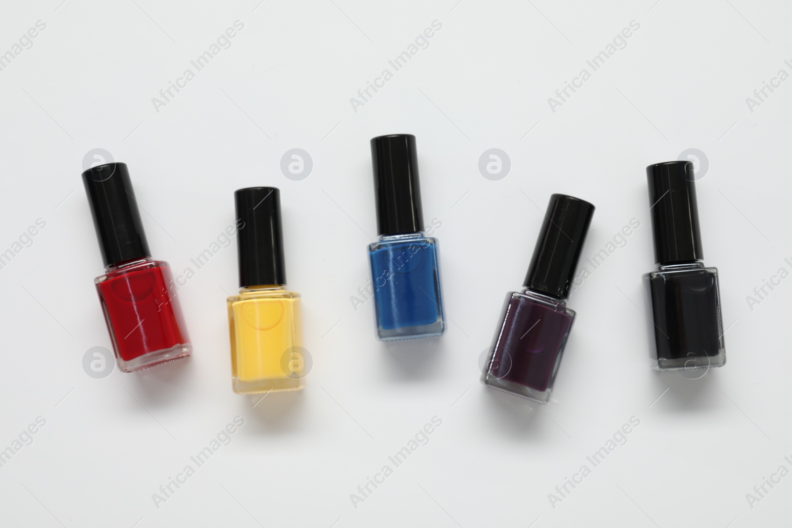 Photo of Nail polishes on white background, flat lay