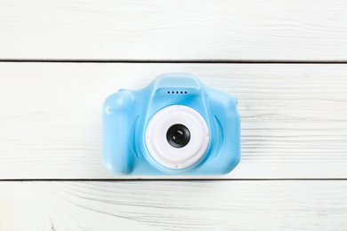 Light blue toy camera on white wooden background, top view