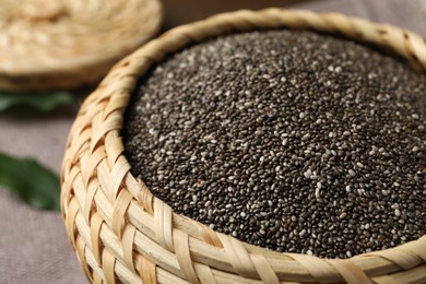 Photo of Wicker box with chia seeds on table, closeup