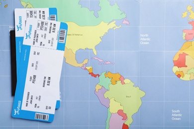 Photo of Tickets and passport on world map, flat lay. Travel agency concept