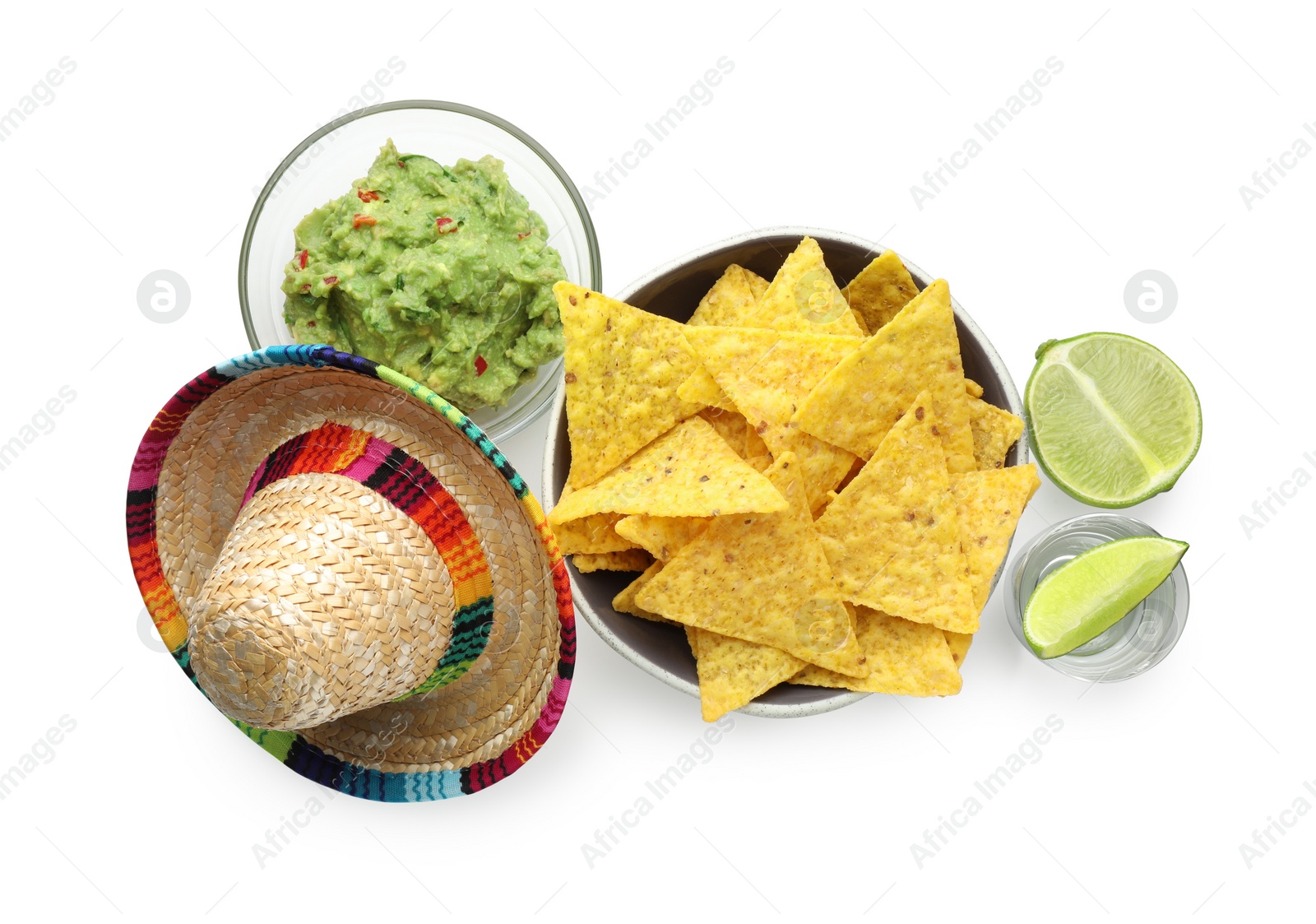 Photo of Mexican sombrero hat, tequila with lime, nachos chips and guacamole in bowls isolated on white, top view