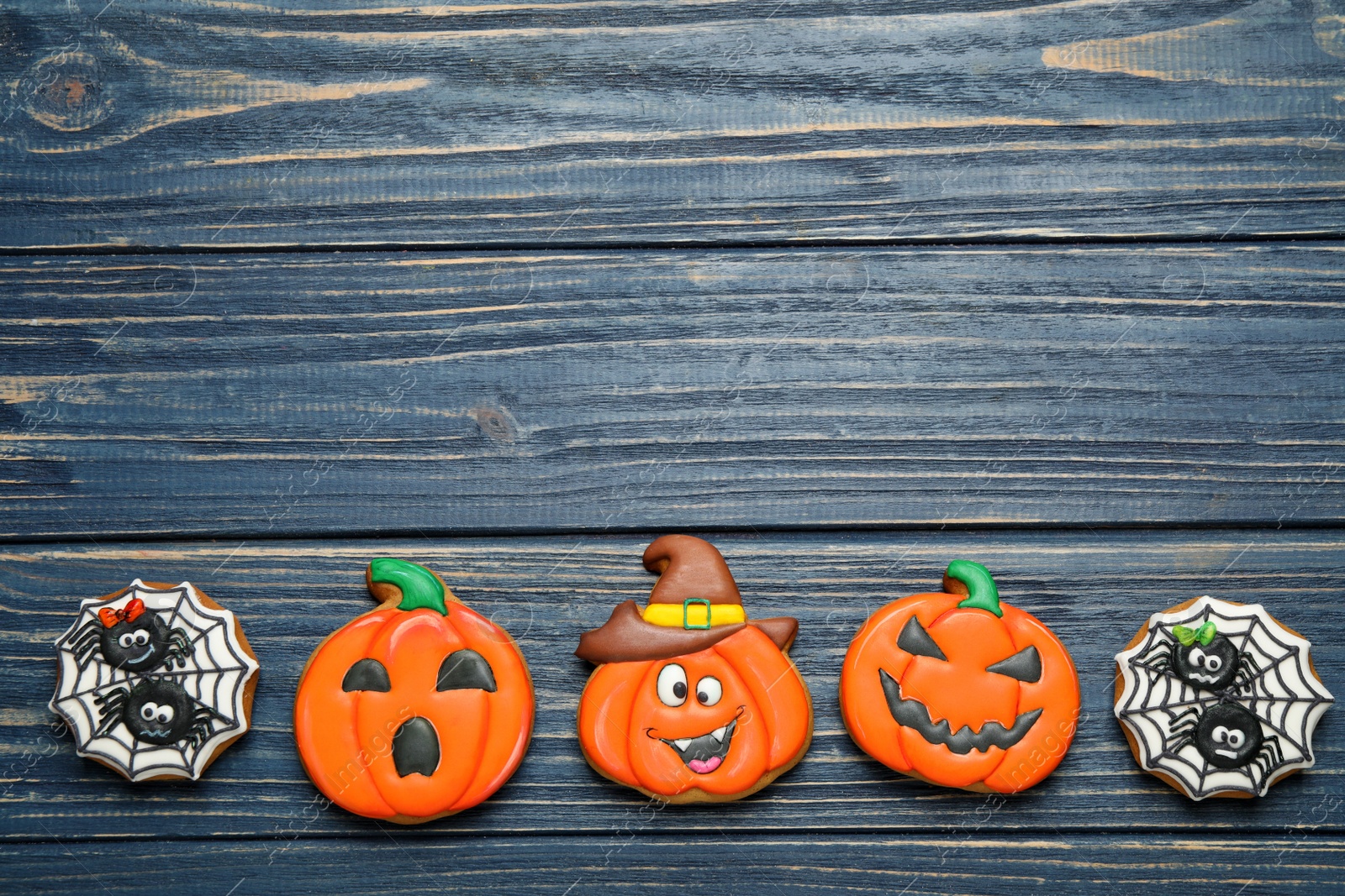 Photo of Tasty Halloween cookies on blue wooden table, flat lay. Space for text