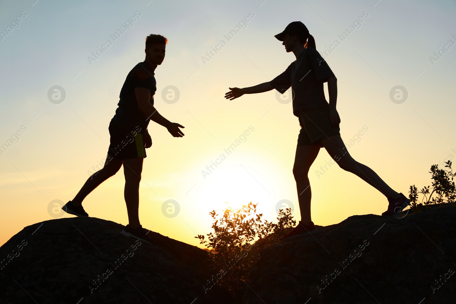 Photo of Hiker helping friend outdoors at sunset. Help and support concept