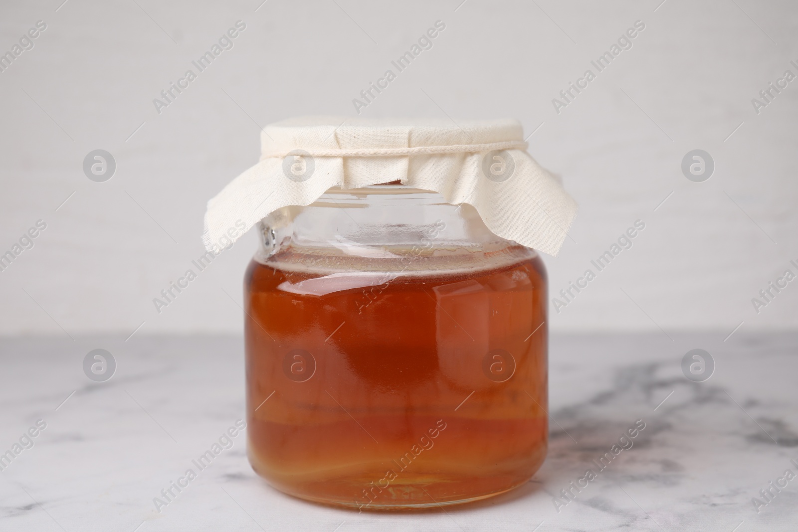 Photo of Tasty kombucha in glass jar on white marble table